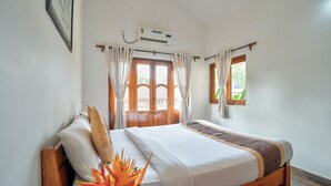 A hotel room with a wooden bed, white bedding, a ceiling fan, and a window with curtains.