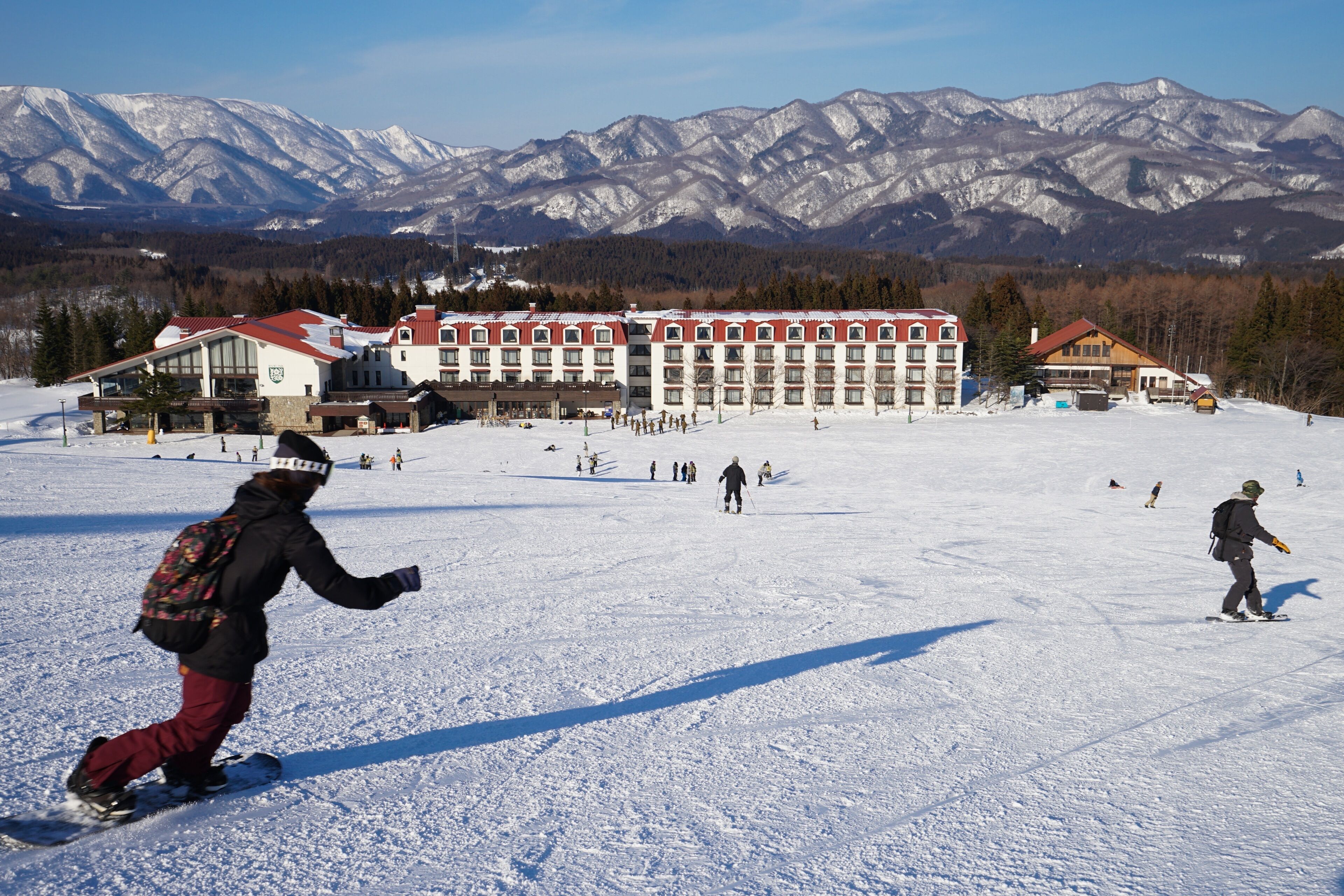 A snow-covered ski resort with a large lodge and mountains in the background.