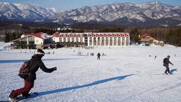 A snow-covered ski resort with a large lodge and mountains in the background.