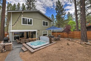 A two-story house with a patio area, a hot tub, and a covered seating area.
