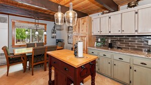 Een keuken met houten kastjes, een eettafel met stoelen en hanglampen.