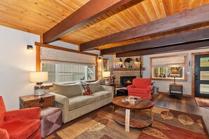 Una sala de estar acogedora con chimenea, un sofá, un sillón rojo y una mesa de centro.