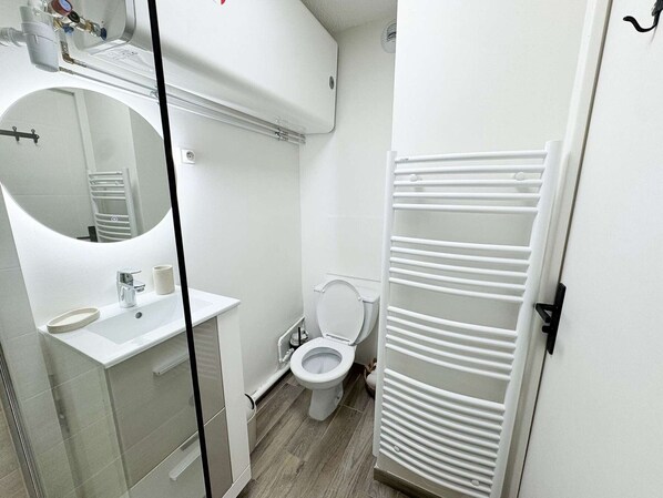 A modern bathroom with a white sink, mirror, and toilet.