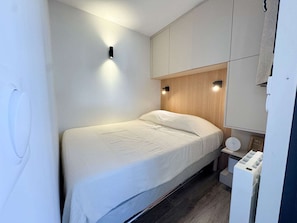 Un dormitorio moderno con cama, iluminación empotrada y cabecero de madera.