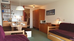 A compact living space with a kitchenette, a dining area, and a sofa. - Cozy studio near slopes with WIFI (Montvalezan-La Rosière)