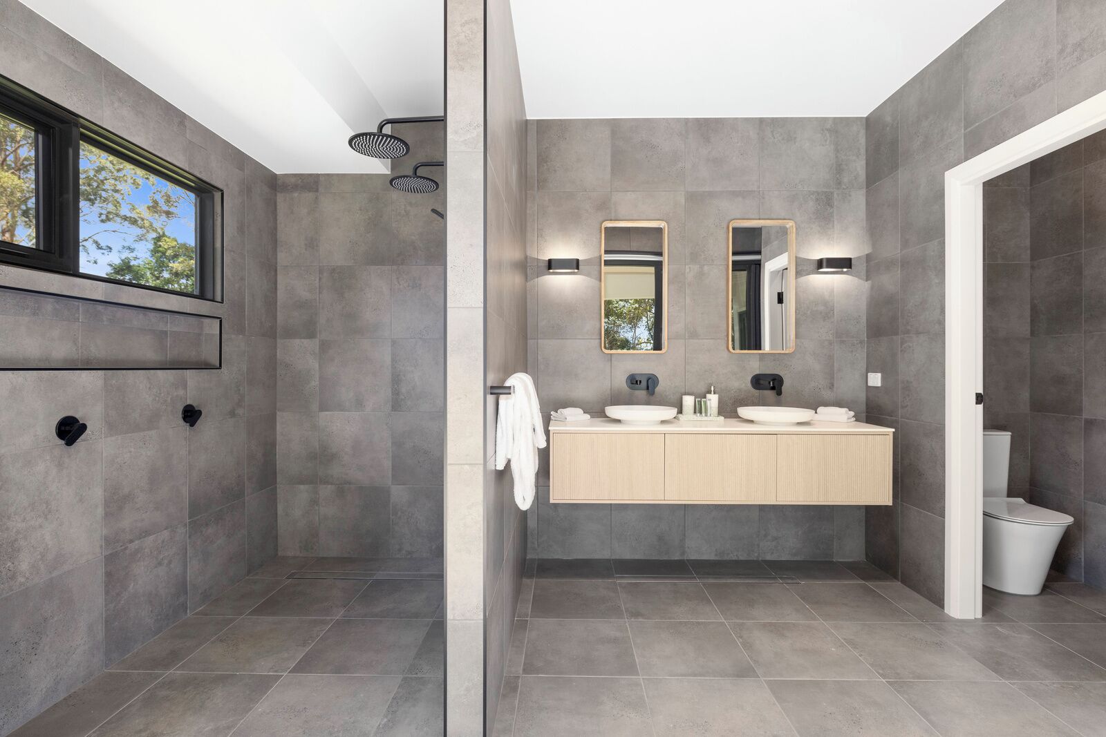 A modern bathroom with a walk-in shower, a large mirror, and a vanity with two sinks.