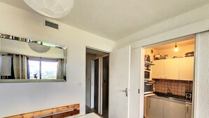 Une cuisine de taille réduite, équipée d’un évier, d’une cuisinière et de placards. On y trouve également un banc en bois et une table dans la pièce adjacente.