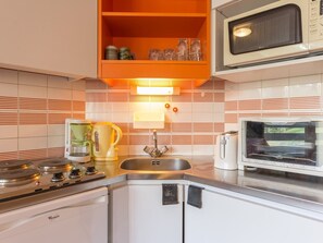 Una cocina compacta con estufa, microondas y fregadero.