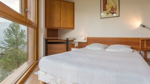 A bedroom with a bed, wooden wardrobe, and a painting on the wall. - Comfortable apartment near slopes with WIFI (Montvalezan-La Rosière)