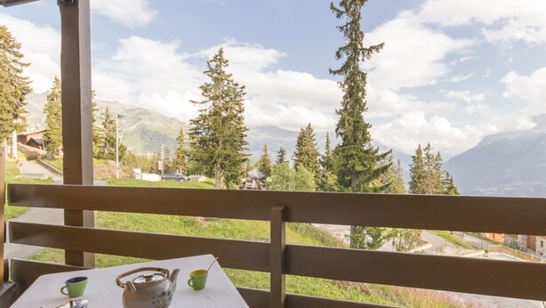 A balcony with a table set for tea, overlooking a mountainous landscape with trees and a clear sky. - Comfortable apartment near slopes with WIFI (Montvalezan-La Rosière)