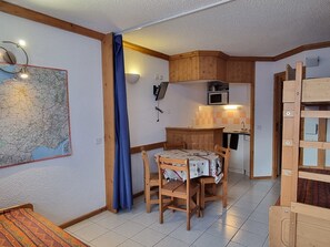 A compact living space with a dining area, kitchenette, and a map on the wall.