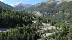 A mountainous landscape with a road leading to a cluster of buildings surrounded by dense forests.