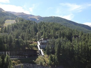A mountain lodge with a wooden exterior, a stone wall, and a glass elevator leading to the upper floor.