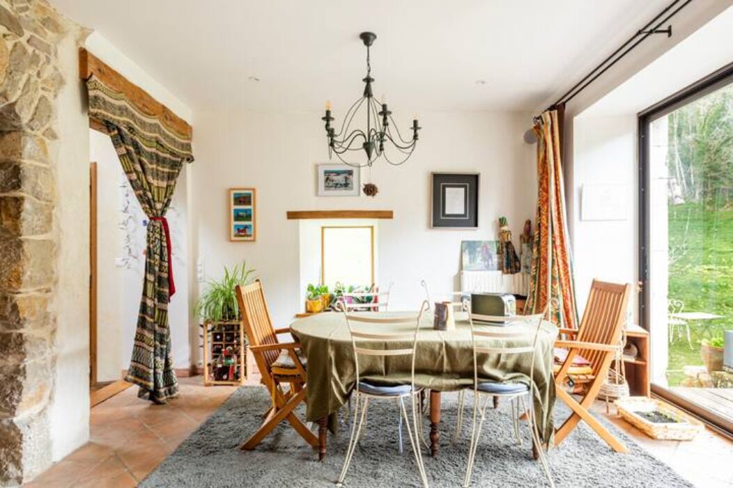 Un comedor con una mesa redonda, sillas, una araña y vistas al exterior.