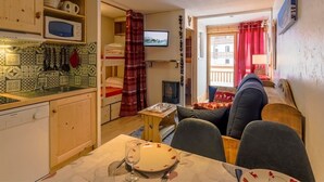 Un ambiente compatto con angolo cottura, zona pranzo e soggiorno dotato di divano e televisione.