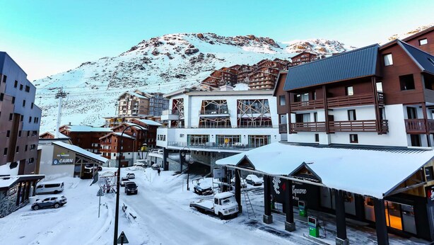 Una strada innevata con edifici, tra cui un albergo con una seggiovia e un mercato.