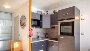 Una cocina compacta con electrodomésticos modernos, un lavamanos y armarios.