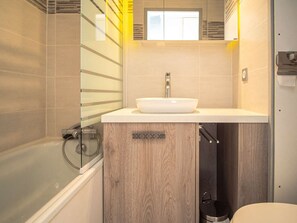A modern bathroom with a glass shower enclosure, a white sink, and a wooden vanity. - Val Thorens - Apartment for 6, 3 Gold Flakes, 2 baths, near ski lifts (Val Thorens)