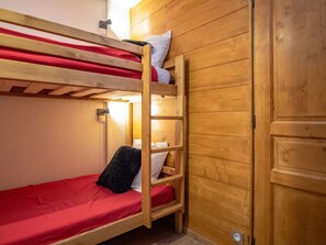 Una litera con un colchón rojo y una escalera de madera.