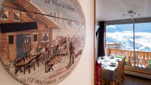 Un comedor con vistas panorámicas a la montaña, una mesa de madera y sillas.