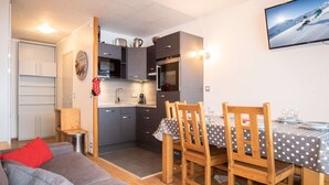 Un espacio habitable compacto con kitchenette, comedor y sofá.