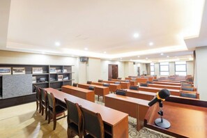 A conference room with rows of tables and chairs, a podium, and a carpeted floor. - Zhigu Yashe Hotel (Chongqing)
