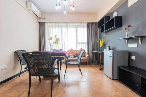 A compact living space with a dining area, a sofa, a small table, and a refrigerator.