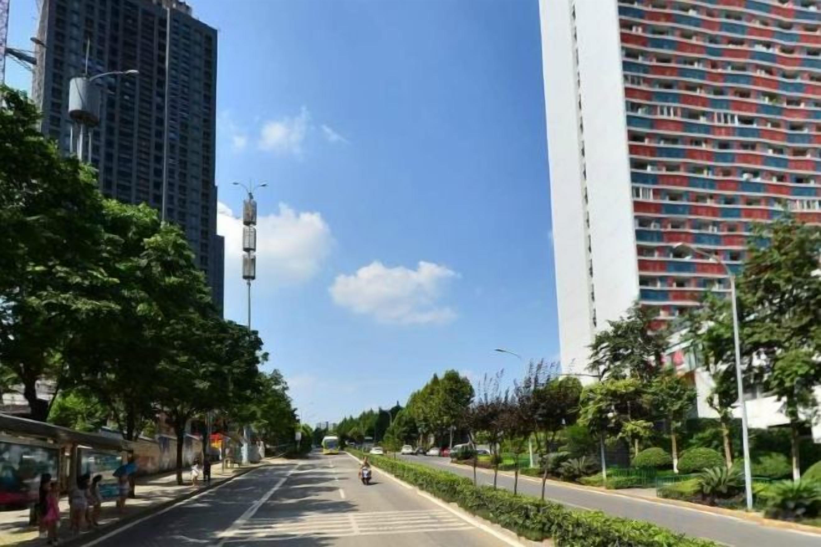 A street with buildings, trees, and a clear sky.