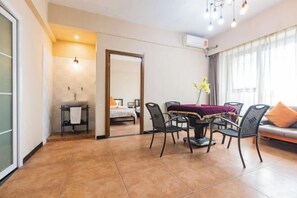 A modern hotel room with a dining area, a bed, and a bathroom.