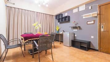 Uma sala de jantar com mesa, cadeiras, geladeira e um armário de parede.