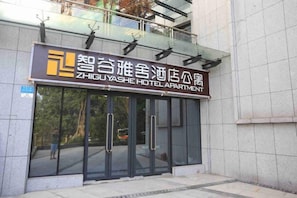 Der Eingang zum Zhiguyash Hotel Apartment mit einer Glasfassade und einem Schild über den Türen.