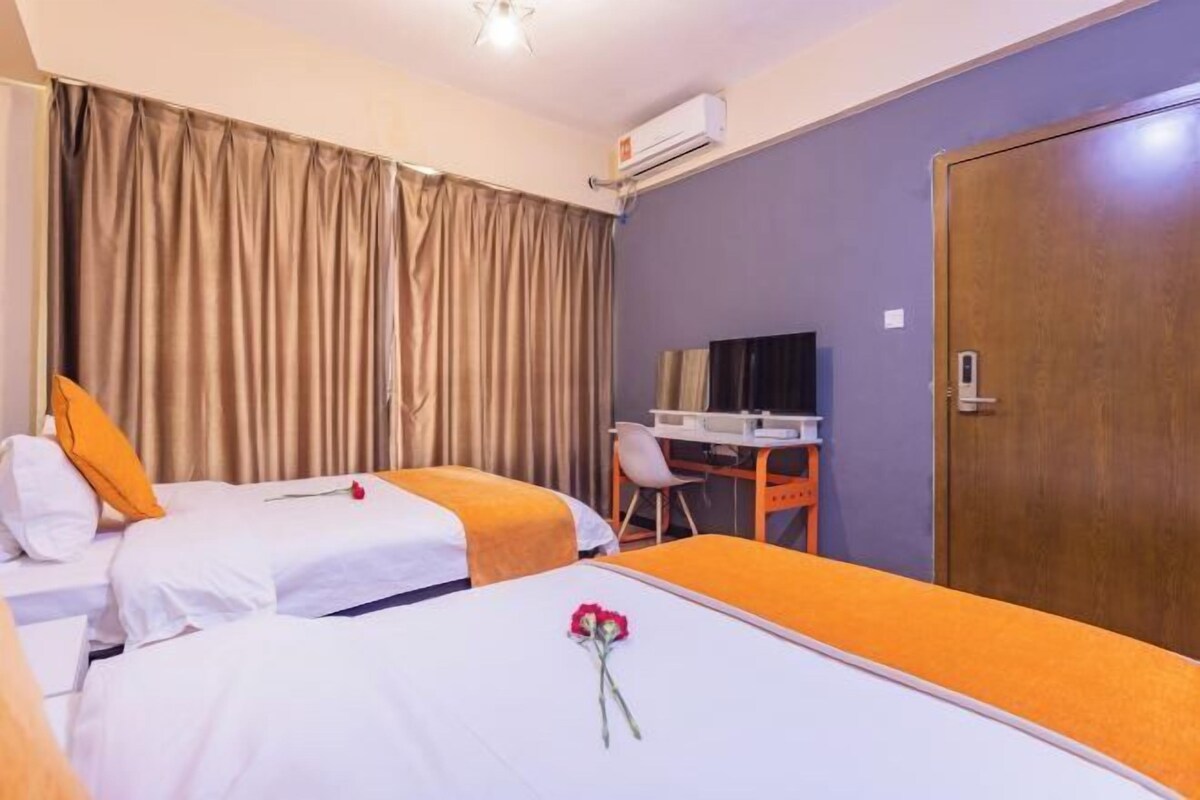 A hotel room with two beds, a desk, a television, and a door.