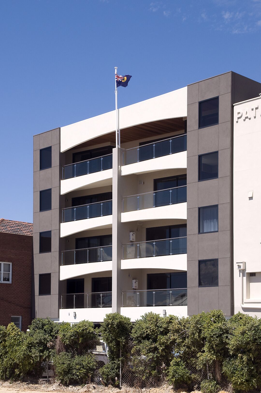 Un edificio a più piani con un'antenna, balconi e un cartello con la scritta 'PAT'.