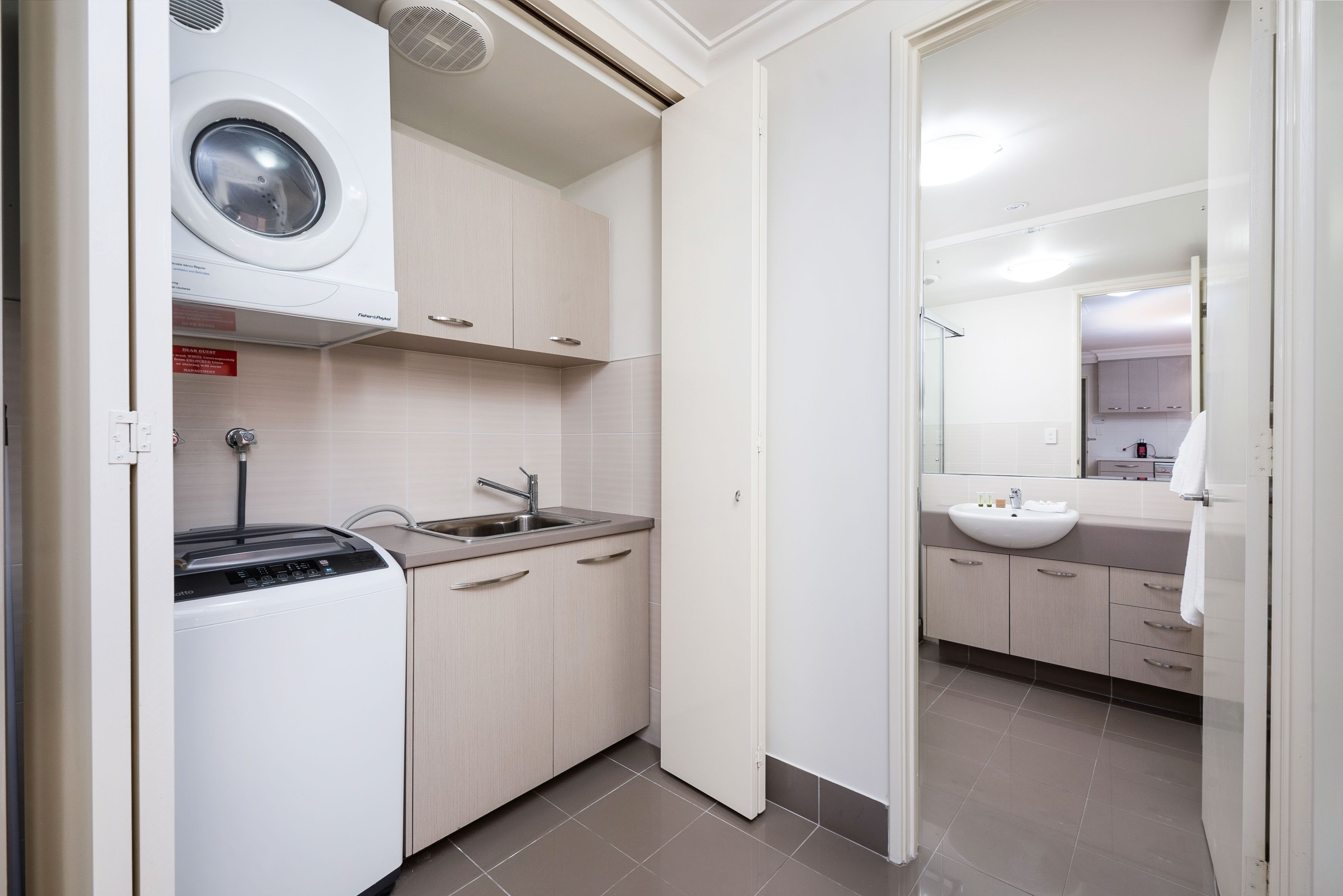 A compact kitchen with a washing machine, sink, and cabinets.