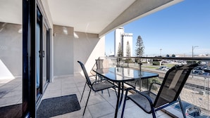 A balcony with a table and chairs, a view of a cityscape, and a clear sky. - Fremantle Harbourside  Apartments (Fremantle)