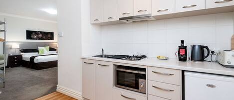 A compact kitchen with a built-in oven, a gas stove, and a coffee maker.