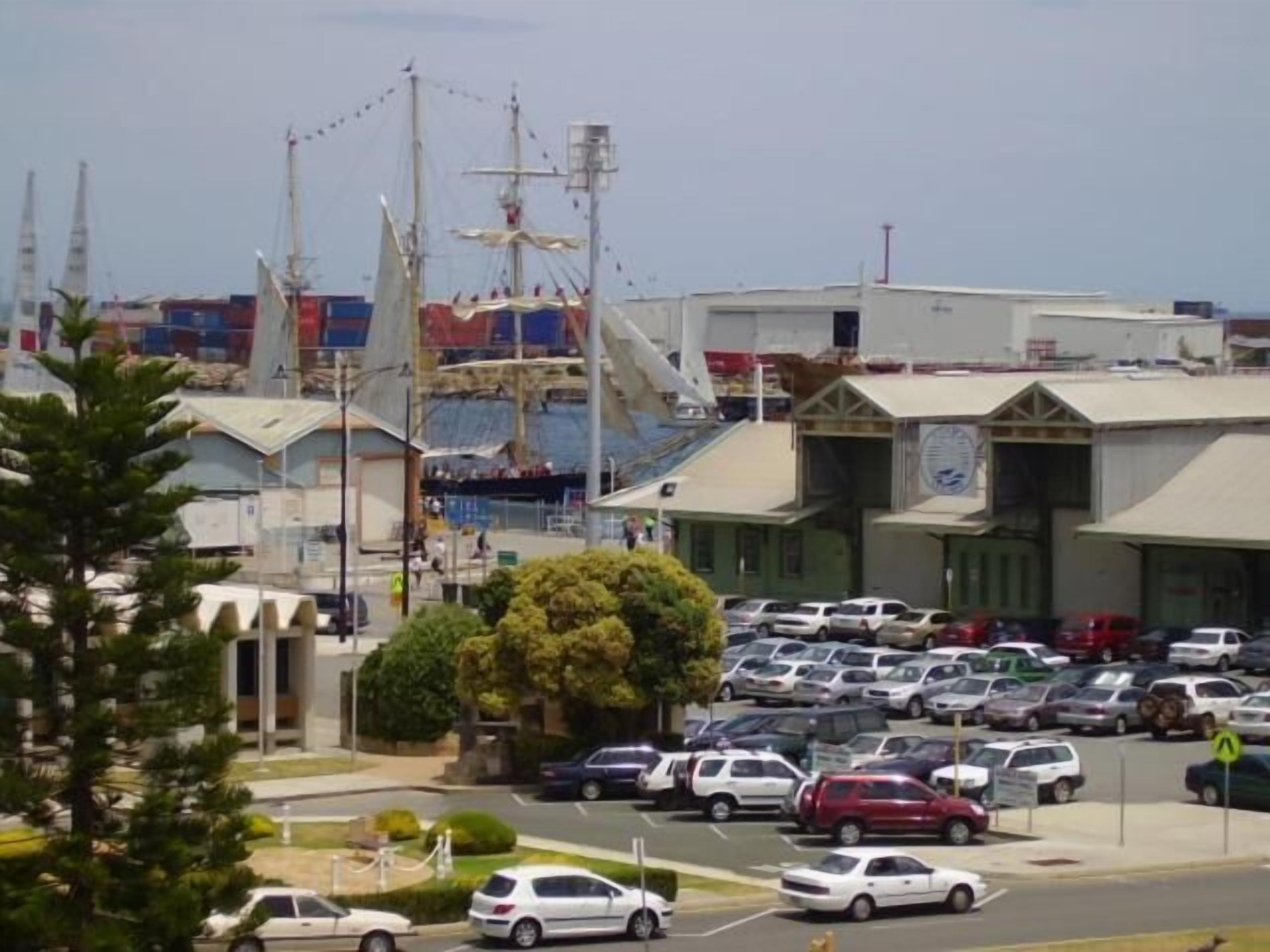 A parking lot with multiple cars, a building with a sign, and a crane in the background.