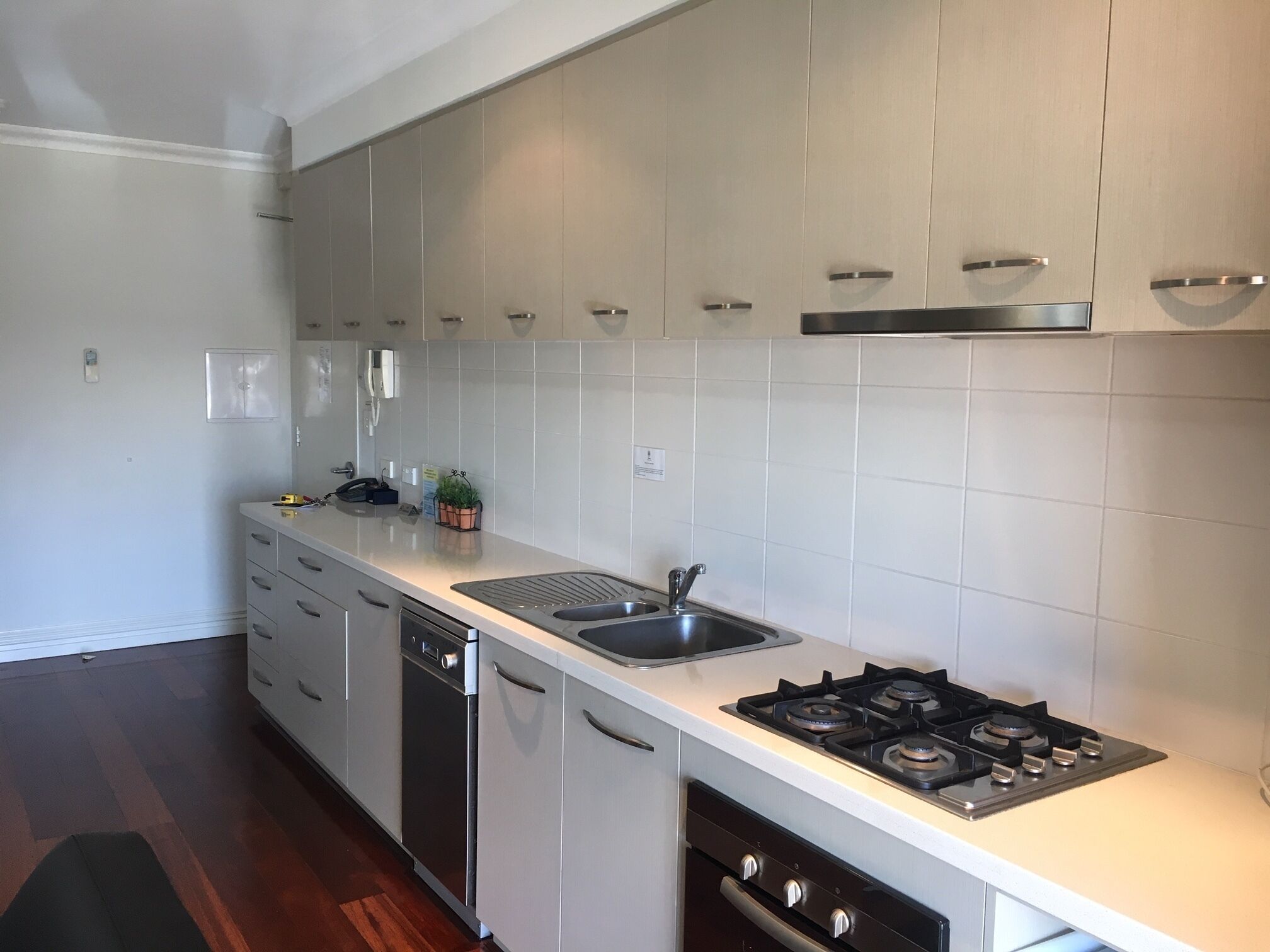 A modern kitchen with white cabinets, a stainless steel sink, a gas stove, and a dishwasher.