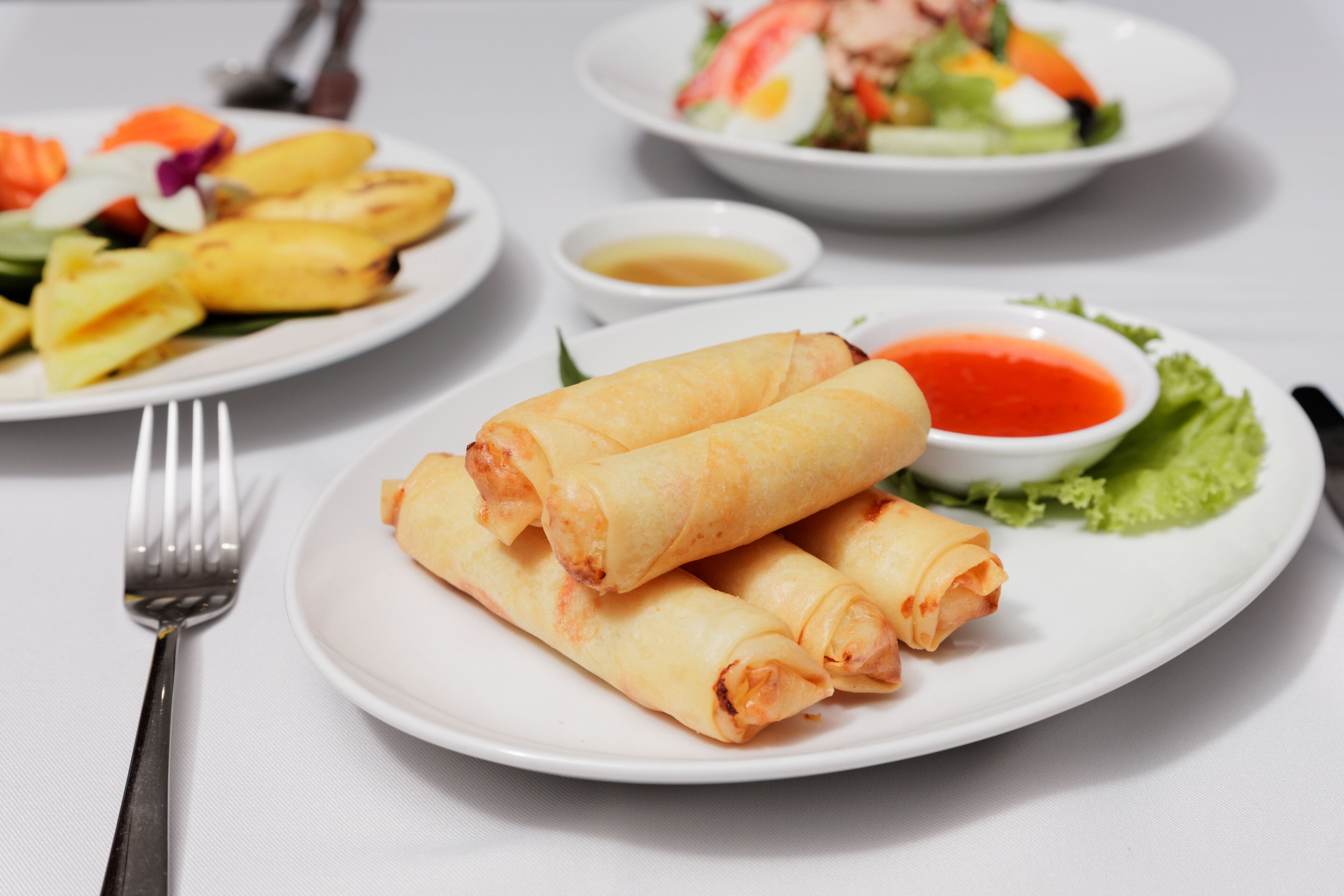 A plate of spring rolls with dipping sauce and a side salad.