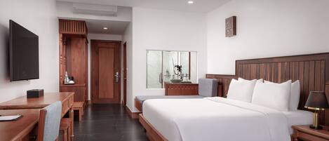 A modern hotel room with a large bed, a desk with a chair, a television, and a bathroom with a mirror.