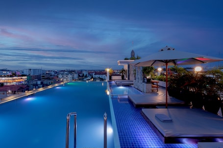 Una piscina al aire libre, sombrillas, sillones reclinables de piscina