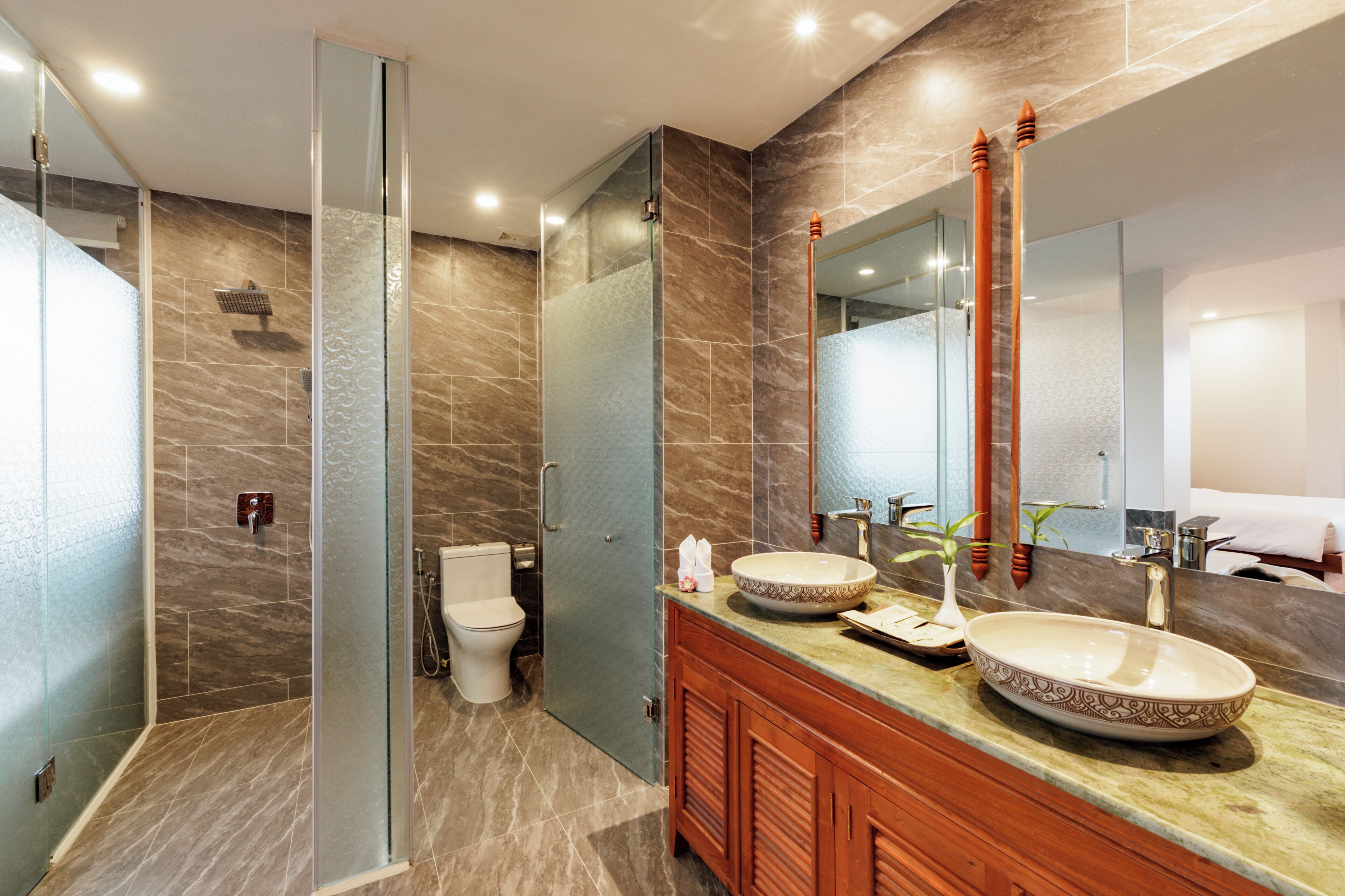 A modern bathroom with a glass-enclosed shower, a large mirror, and a vanity with a bowl sink.