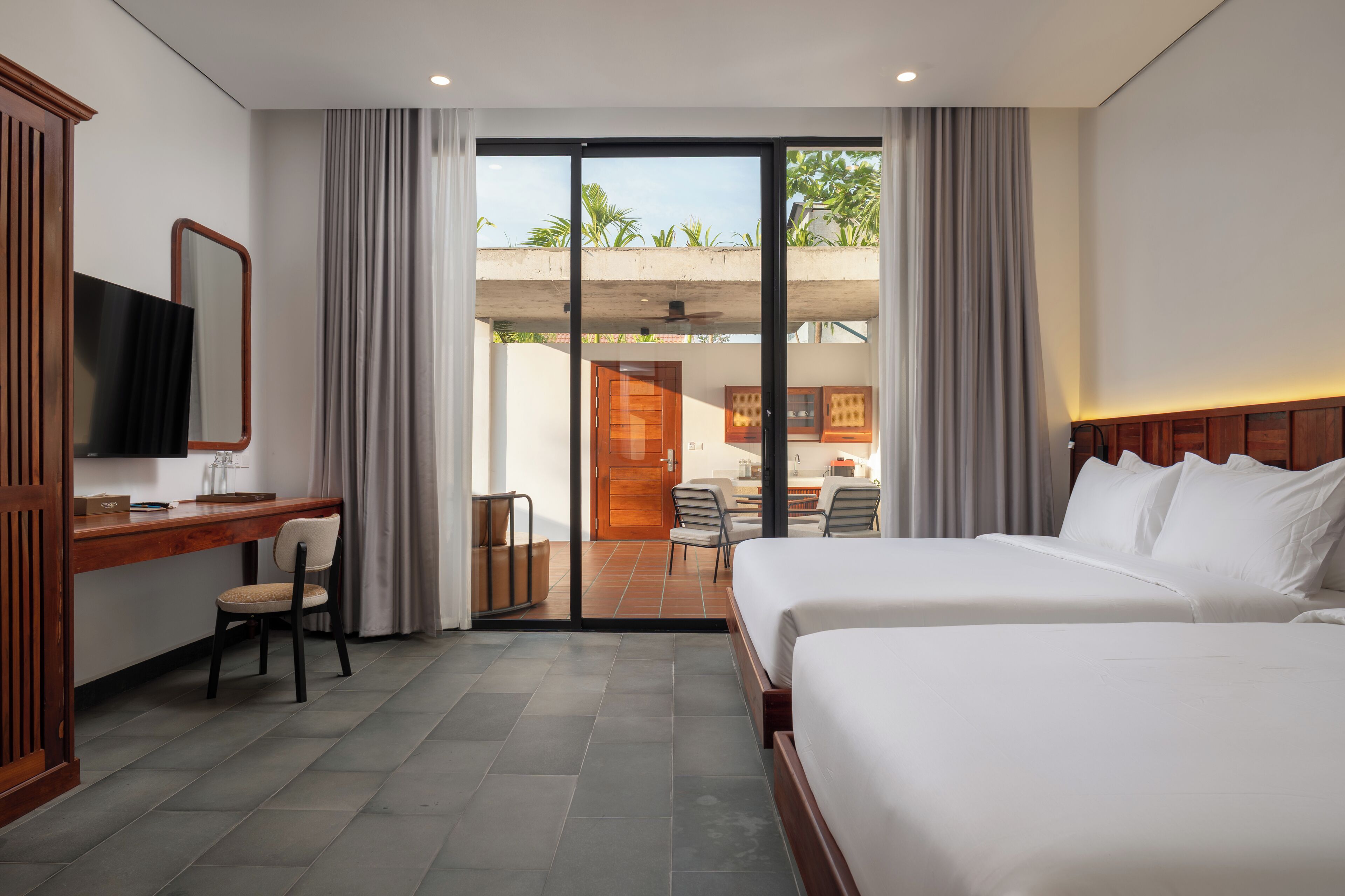 A hotel room with a bed, desk, chair, and a television.