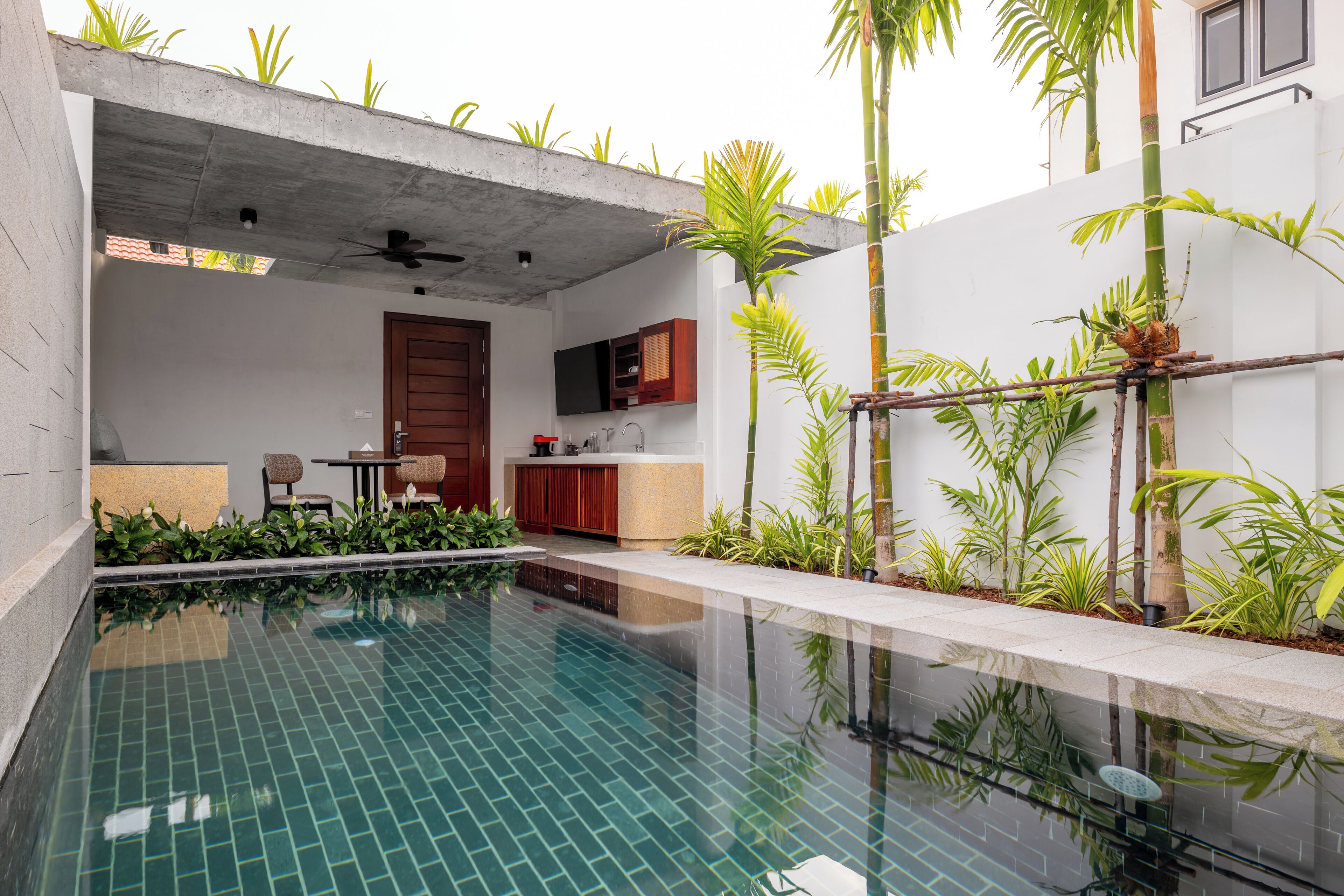A modern outdoor pool area with a kitchen and seating area.