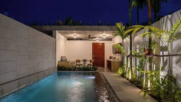 A swimming pool with a patio area, a door leading to a room, and a small kitchen area.