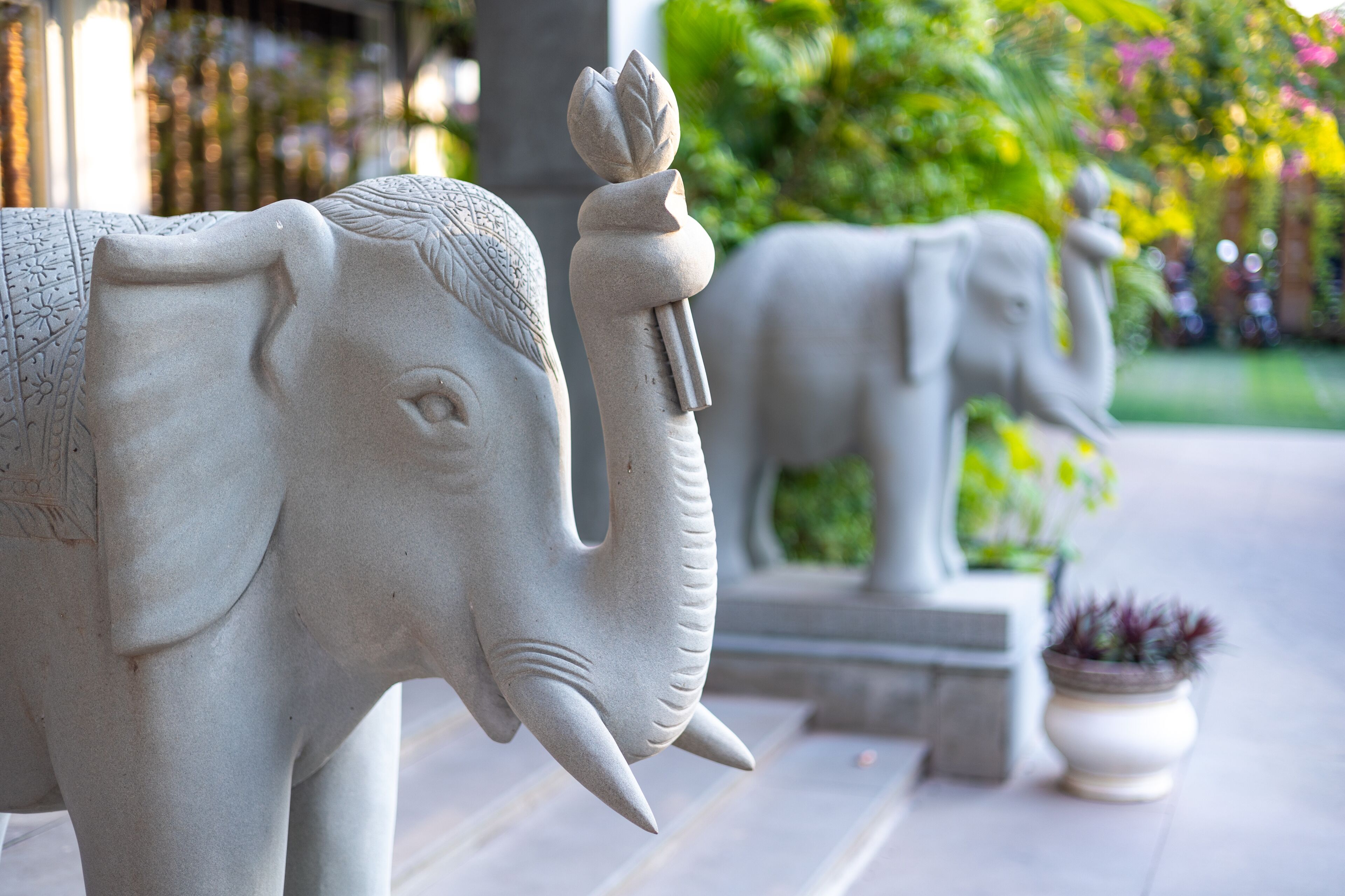 A stone elephant sculpture in a garden setting.