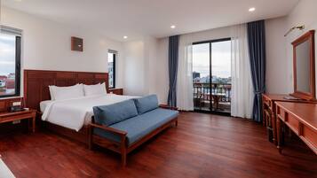 Habitación de hotel con una cama grande, un sofá, un escritorio y un balcón con vistas.