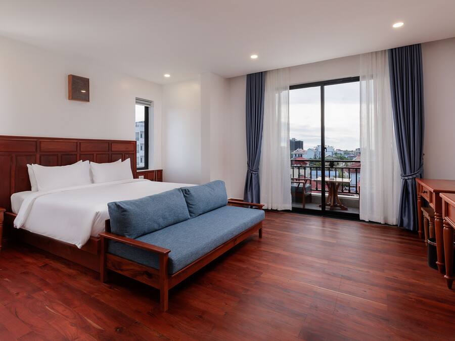Habitación de hotel con una cama grande, un sofá, un escritorio y un balcón con vistas.