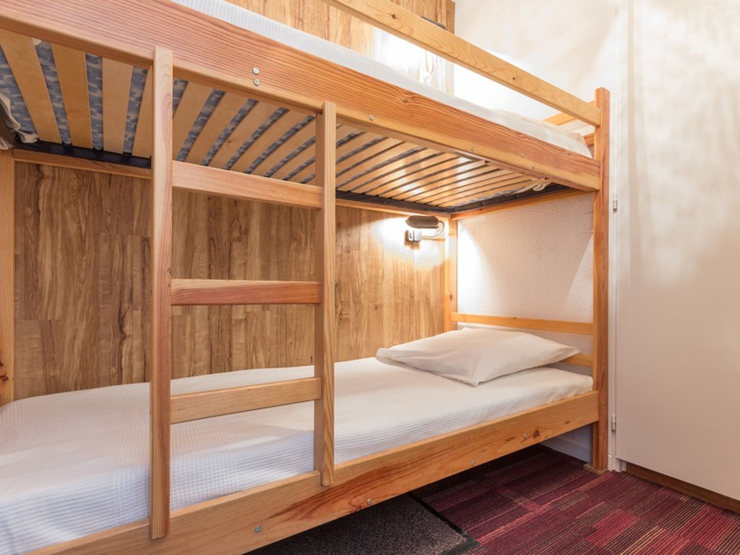 A bunk bed with a wooden frame, a mattress, and a pillow.