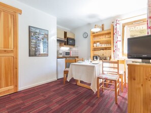 A compact living space with a kitchenette, dining area, and a television.
